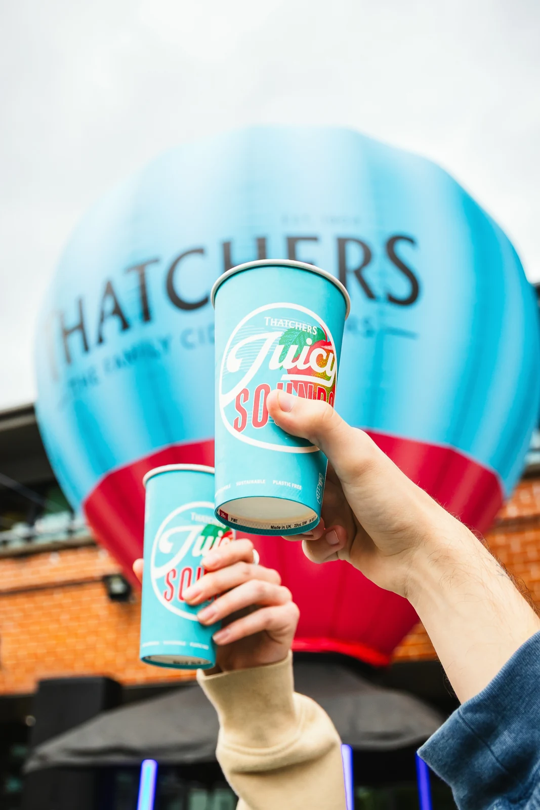 Two Thatchers drinks raised in front of the branded hot air balloon
