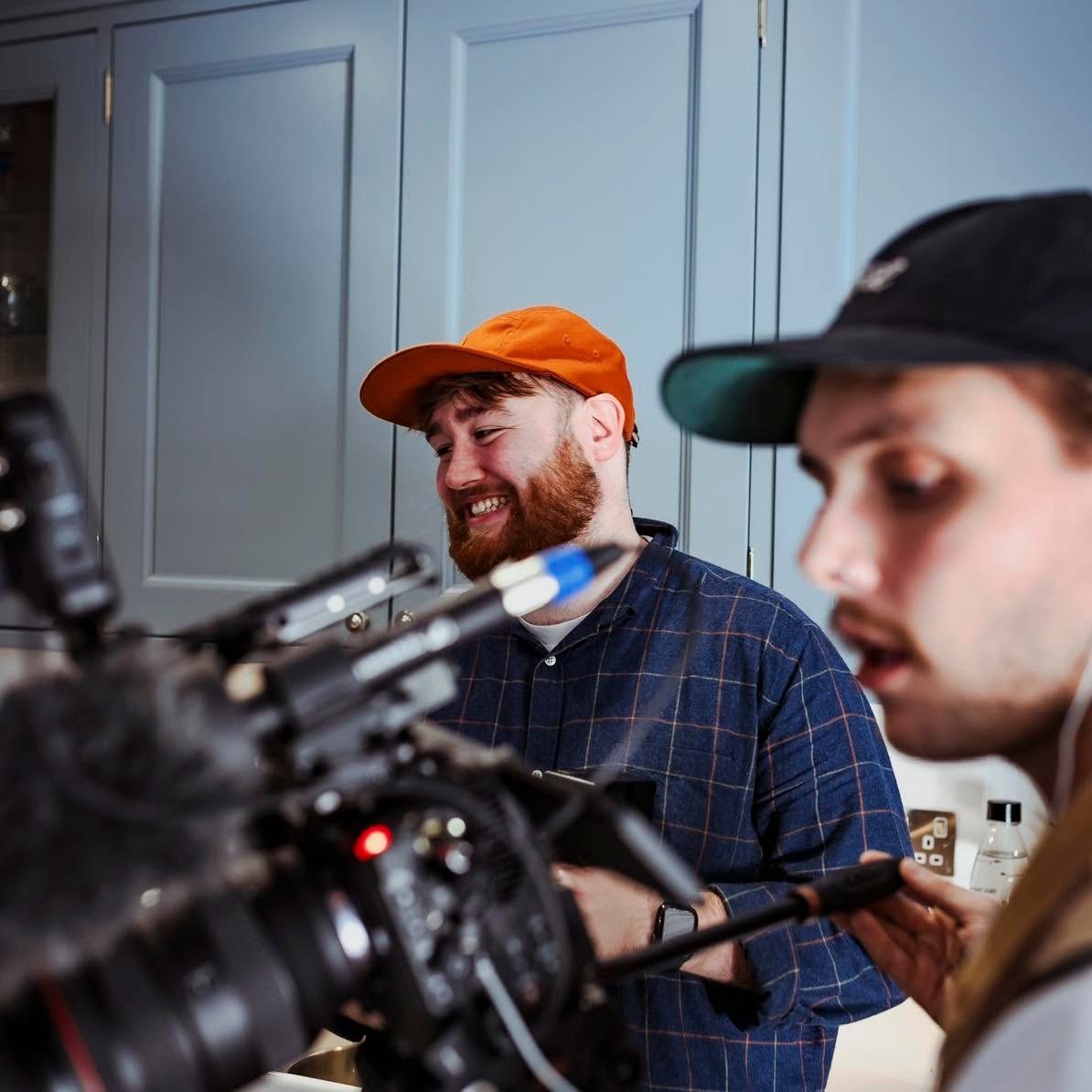 Jordan Baird in an orange cap, working behind a camera on a shoot